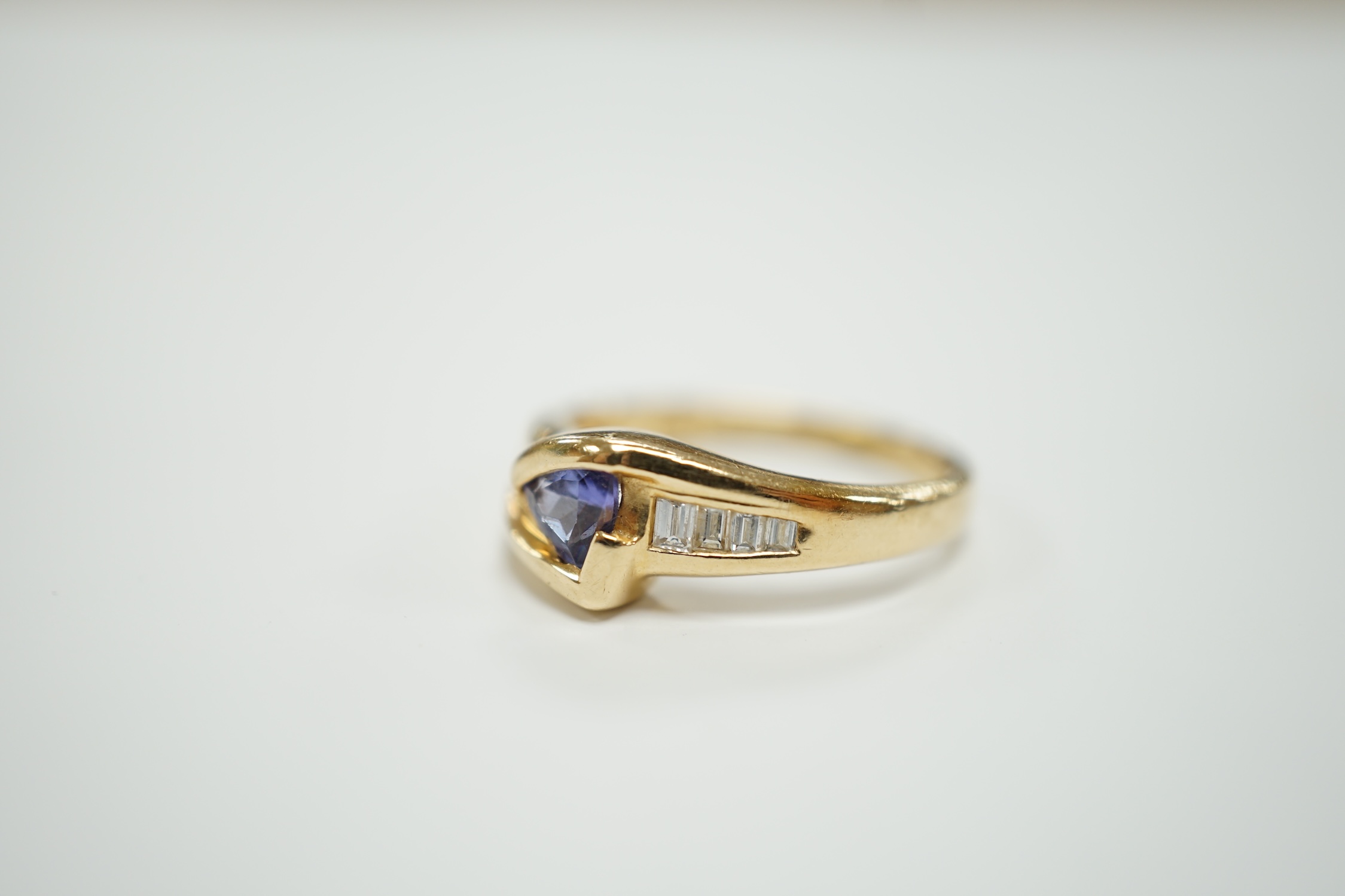 A modern 14ct and single stone tanzanite and graduated eight stone baguette cut diamond set ring, size K/L, gross weight 2.9 grams.